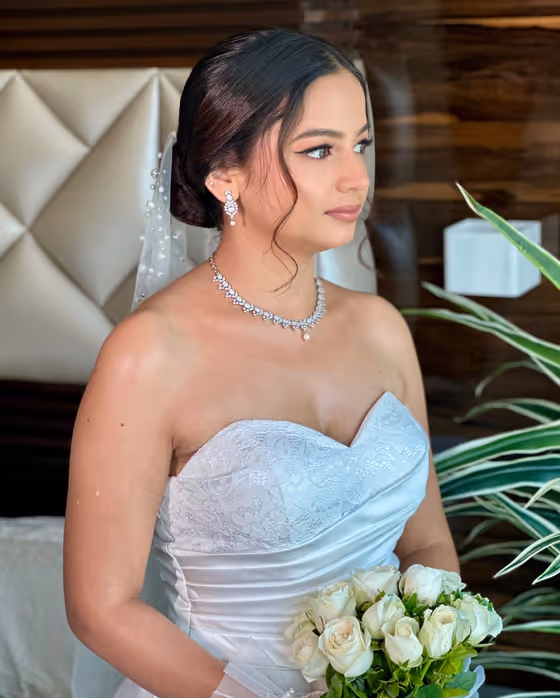 Bride in a white gown with a low chignon and diamond necklace