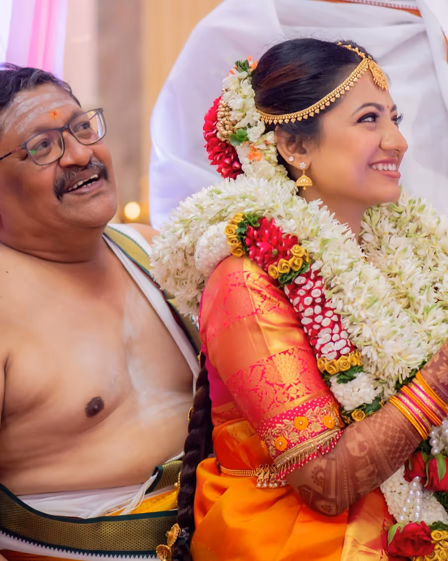 A bride with a jasmine garland laughing with family on her wedding morning